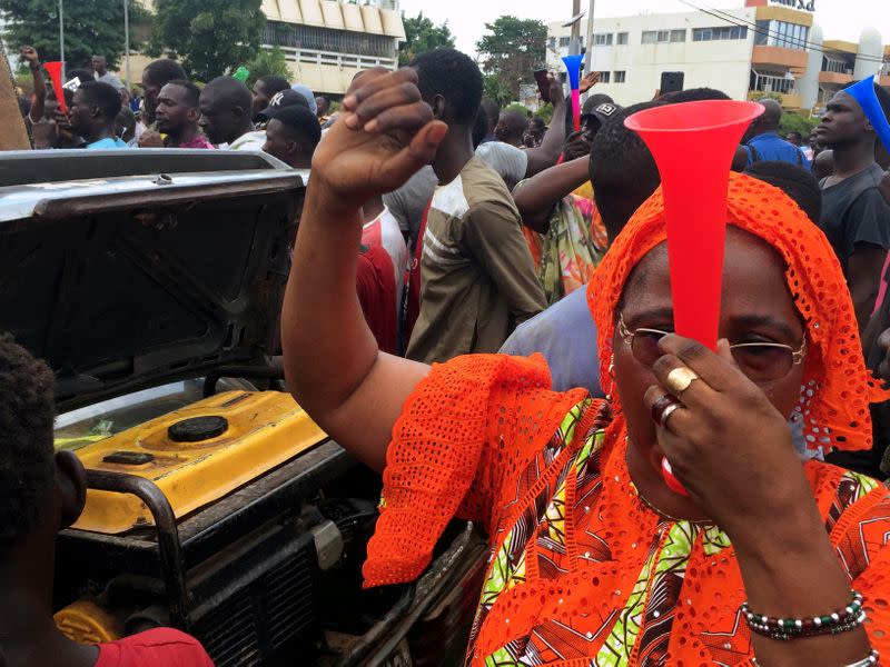 Opposition supporters react to the news of possible military mutiny, at Independence Square in Bamako