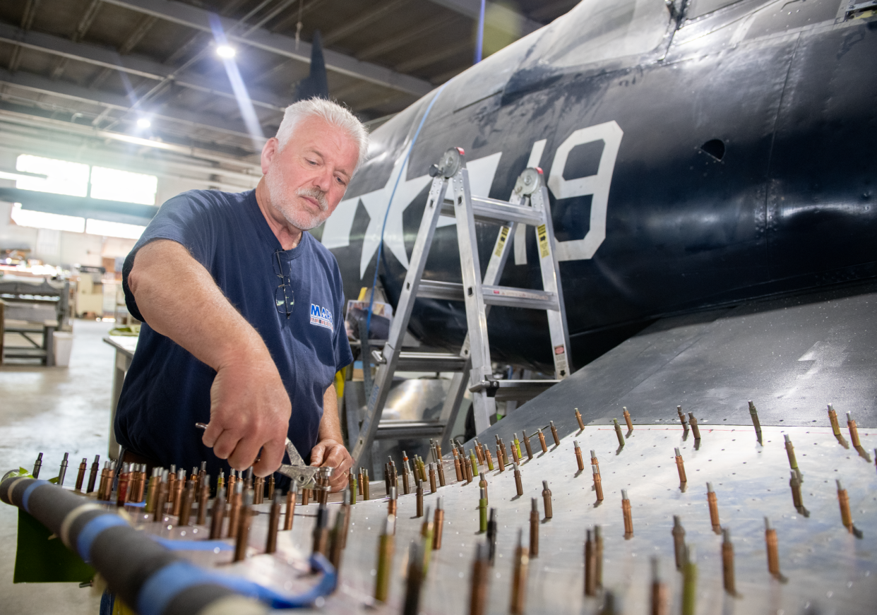 Dennis Bachtel tends to the reconstruction of a Goodyear Corsair fighter plane May 8 at the MAPS Air Museum in Green. Bachtel demonstrates using cleco fasteners on the inner wing, which are used before adding rivets at a later time.