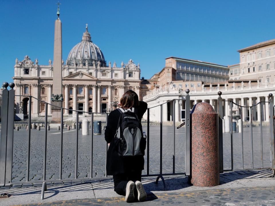 A woman prays on her knees in front of an empty St. Peter's Square as Pope Francis gives his weekly general audience via transmitted video a day after the Vatican closed the square and Basilica due to coronavirus concerns, as seen from Rome, Italy March 11, 2020. REUTERS/Guglielmo Mangiapane