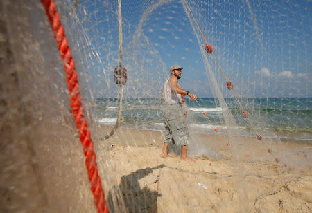 A Palestinian fisherman prepares fishing net on a beach in the northern Gaza Strip August 21, 2017. REUTERS/Mohammed Salem