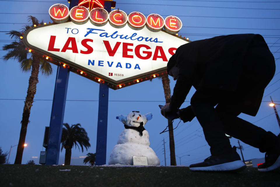 A man, who declined to give his name, takes a picture of a small snowman at the "Welcome to Fabulous Las Vegas" sign along the Las Vegas Strip, Thursday, Feb. 21, 2019, in Las Vegas. Las Vegas is getting a rare taste of real winter weather, with significant snowfall across the metro area in the first event of its kind since record keeping started back in 1937. (AP Photo/John Locher)