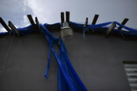 The home of 85-year-old Carmen Lacen, not habitable after Hurricane Maria, is covered by a torn, blue tarp, commonly used after the passage of storms, in Loiza, Puerto Rico, Thursday, May 28, 2020. Caribbean islands have rarely been so vulnerable as an unusually active hurricane season this year threatens a region still recovering from recent storms as it fights a worsening drought and a pandemic that has drained budgets and muddled preparations. (AP Photo/Carlos Giusti)