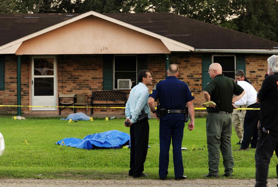 Law enforcement investigators investigate the scene of a stabbing and shooting at a home in Sunset Louisiana