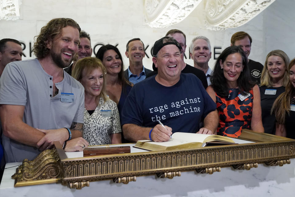 Dutch Bros Coffee Co-founder and Executive Chairman Travis Boersma, center, poses for photos as he signs the New York Stock Exchange guest book, before ringing the closing bell, Wednesday, Sept. 15, 2021. (AP Photo/Richard Drew)