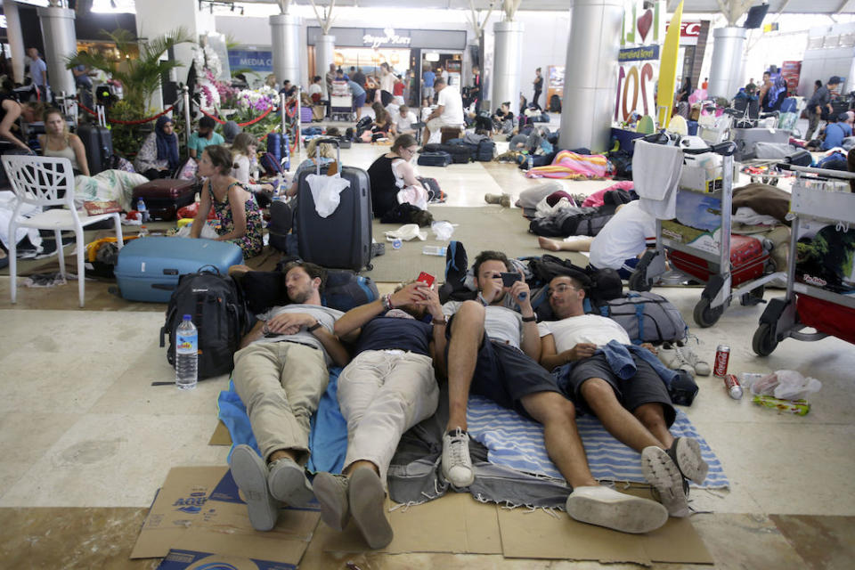 Stranded foreign tourists rest on the floor while waiting for their flights at Lombok International Airport (Picture: AP)