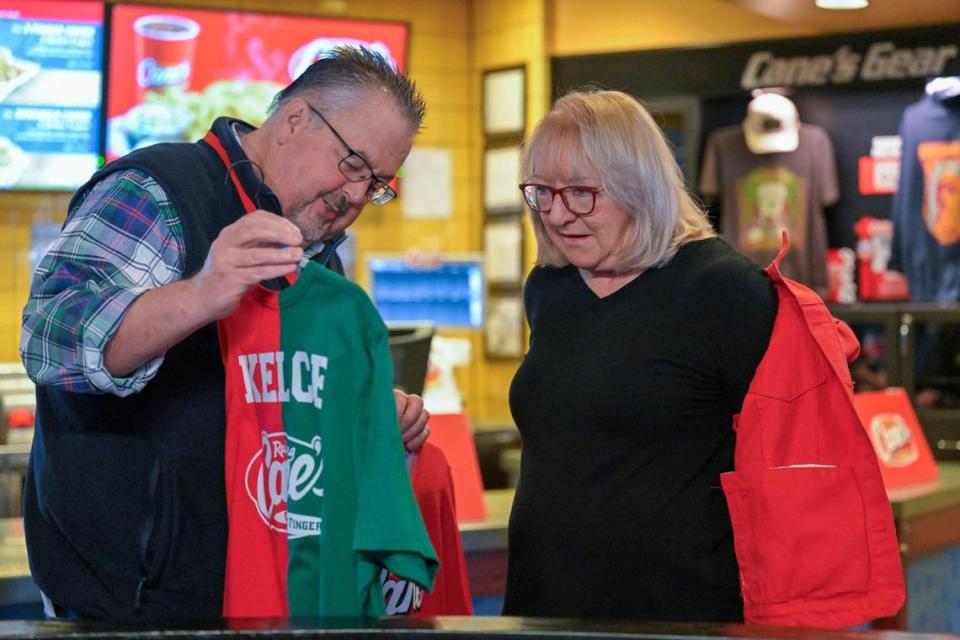 John Mathias of Rocketmail Productions of Dallas, presented a red and green shirt to Donna Kelce, the mother of Chiefs tight end Travis Kelce and Eagles center Jason Kelce, upon her arrival at Raising Cane’s on Monday, Nov. 20 2023, in Overland Park. Mathias was on hand to direct a video being shot with Kelce at the fast food restaurant.