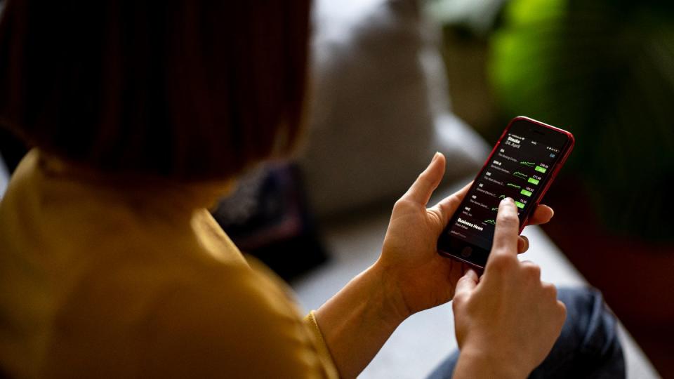 Eine Frau beobachtet mit ihrem iPhone die Aktienkurse in der App Stocks.