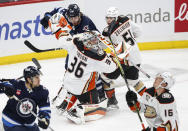 Anaheim Ducks goaltender John Gibson (36) becomes entangled with Winnipeg Jets' Adam Lowry (17) and Ducks' Olen Zellweger (51) during first-period NHL hockey game action in Winnipeg, Manitoba, Friday, March 15, 2024. (John Woods/The Canadian Press via AP)