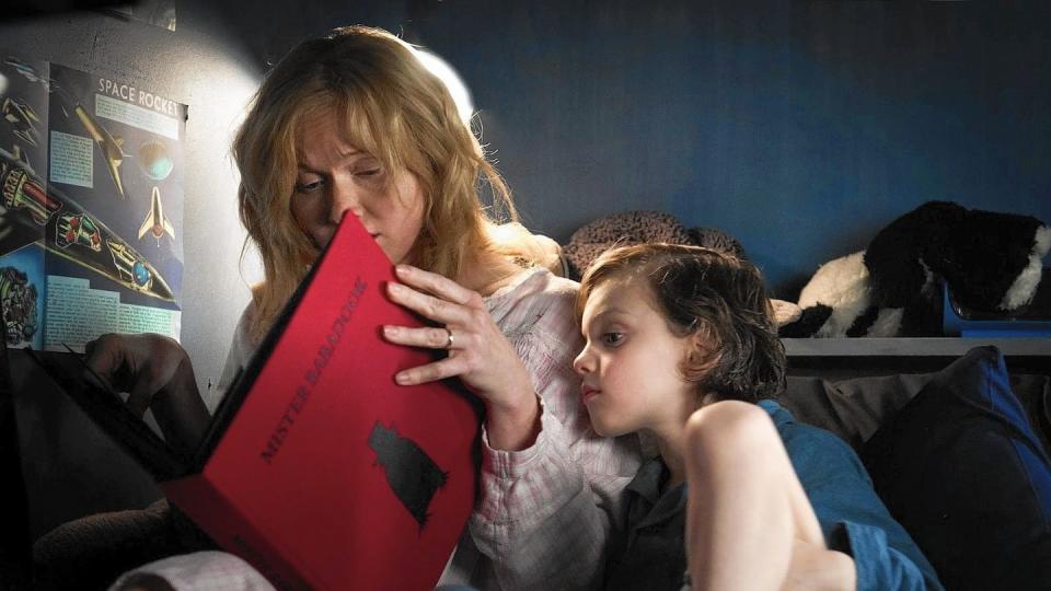 a mother reads a scary book to her son in a scene from the babadook, a good housekeeping pick for best halloween movies