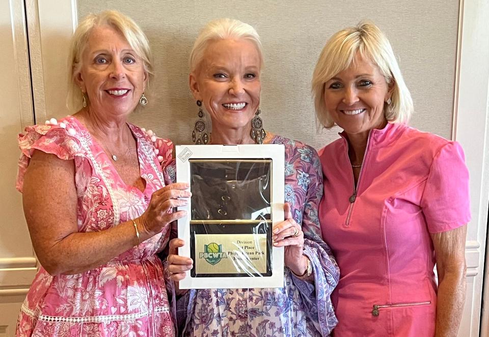 Co-Captain Cathy Moore, from left, Captain Patti Silver and Coach Sean Lee hold the championship plaque for winning the Palm Beach County WTA Division 7 title this tennis season May 11 at Mirasol Country Club.