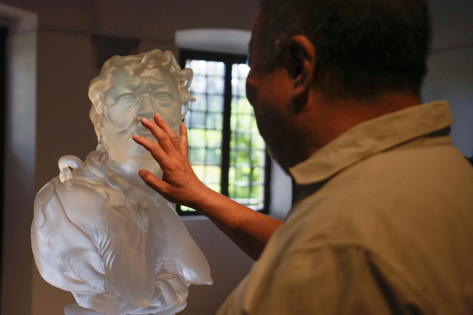 Chinese artist Ai Weiwei touches one of his glass sculpture at the San Giorgio deconsecrated church in Venice, Italy, Friday, Aug. 26, 2022. Chinese artist Ai Weiwei lampoons the surveillance culture and social media with his first ever glass sculpture, made on the Venetian island of Murano, that stands as a warning to the world: "Memento Mori,'' or Latin for "Remember You Must Die." (AP Photo/Luca Bruno)