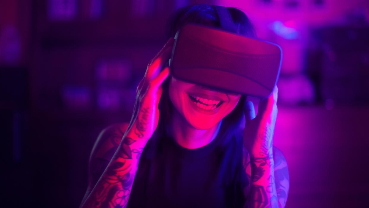  A woman smiles using a headset in the metaverse.  