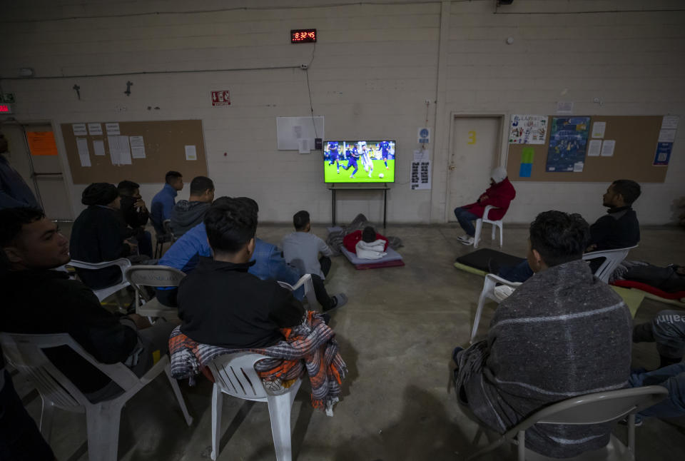 Migrants watch the TV broadcast of the FIFA World Cup final game at a government run shelter in Ciudad Juarez, Mexico, Sunday, Dec. 18, 2022. Texas border cities were preparing Sunday for a surge of as many as 5,000 new migrants a day across the U.S.-Mexico border as pandemic-era immigration restrictions expire this week, setting in motion plans for providing emergency housing, food and other essentials. (AP Photo/Andres Leighton)