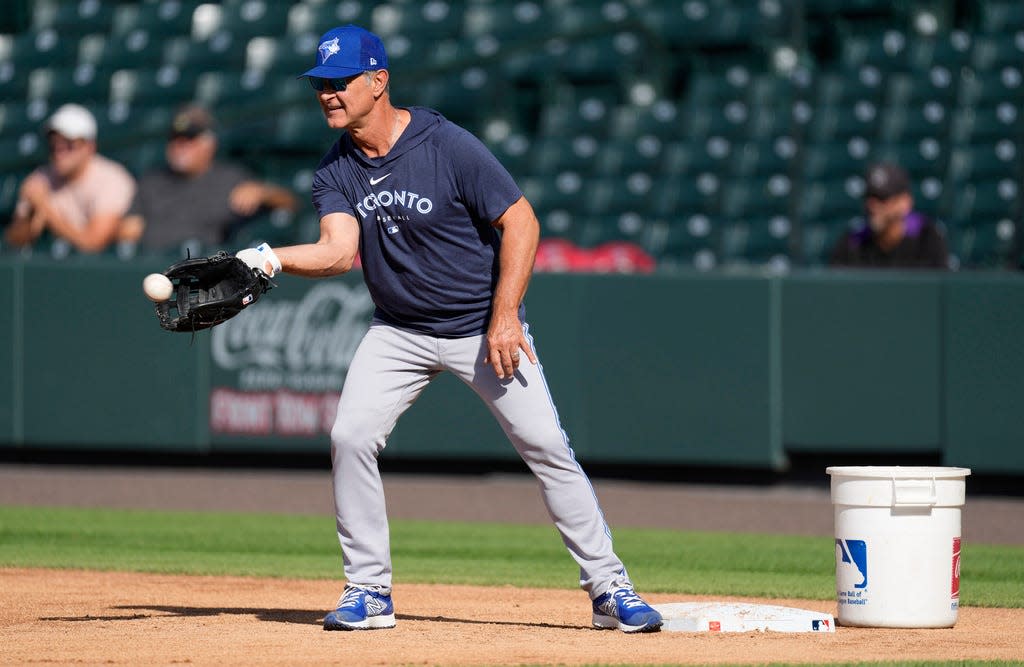 Toronto Blue Jays bench coach Don Mattingly fields a throw while covering first base as players warm up before a baseball game against the Colorado Rockies on Saturday, Sept. 2, 2023, in Denver. (AP Photo/David Zalubowski)