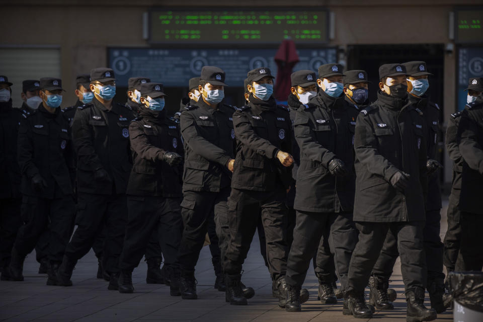 Policemen wear face masks as they march in formation outside the Beijing Railway Station in Beijing, Saturday, Feb. 15, 2020. People returning to Beijing will now have to isolate themselves either at home or in a concentrated area for medical observation, said a notice from the Chinese capital's prevention and control work group published by state media late Friday. (AP Photo/Mark Schiefelbein)