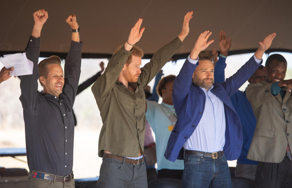 The Duke of Sussex (second left) joins in a group exercise during a tree planting event with local children, at the Chobe Tree Reserve, Botswana.