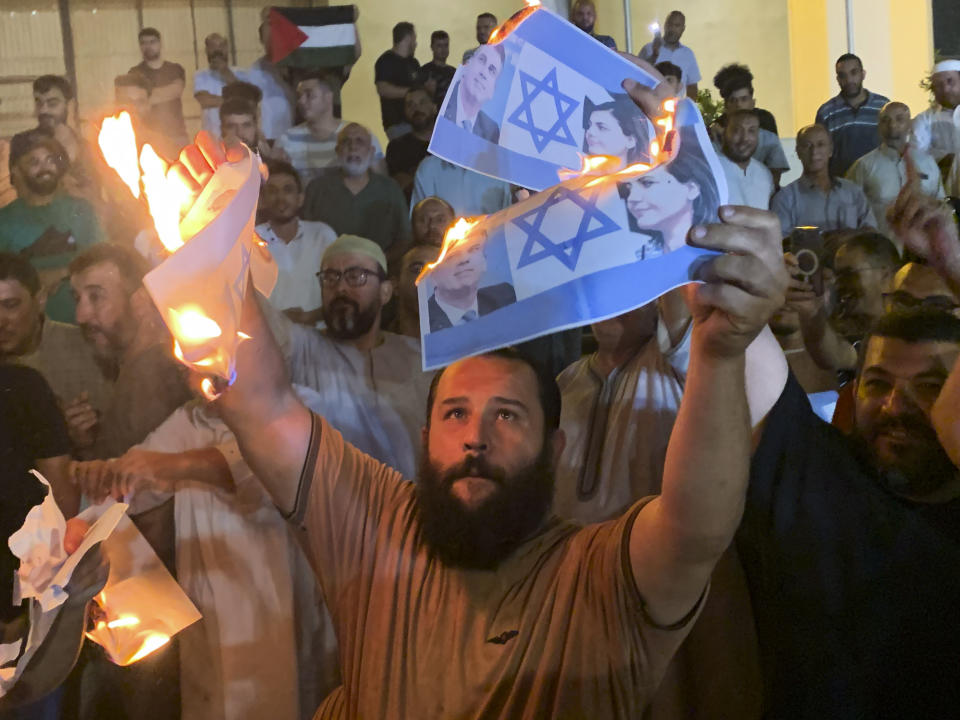 People burn photos showing Israeli Foreign Minister Eli Cohen and his Libyan counterpart Najla Mangoush in Tripoli, Libya, Sunday, Aug. 27, 2023. Cohen and Mangoush met in the Italian capital, Rome, last week, according to the Israeli foreign ministry. (AP Photo/Yousef Murad)