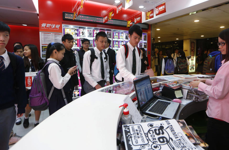 In this Dec. 9, 2013 photo, students queue for marking their attendance for lessons in Modern Education in Hong Kong. Global student rankings out last week highlighted the city’s cutthroat academic atmosphere. Hong Kong teens, along with Shanghai, Singapore, South Korea and Japan, dominated the list compiled by the Organization for Economic Cooperation and Development. Students in East Asian societies have long relied on so-called “cram schools,” but Hong Kong has taken them to a new level in recent years, with the majority of students attending the city’s nearly 1,000 tutorial centers. Academies use brash marketing, dressing their tutors in miniskirts and high heels or leather jackets to make them look like pop stars. Advertisements for these “tutor kings” and “tutor queens,” as they are known in Cantonese, are splashed on giant roadside billboards, on the sides of shopping malls and on newspaper front pages. (AP Photo/Kin Cheung)