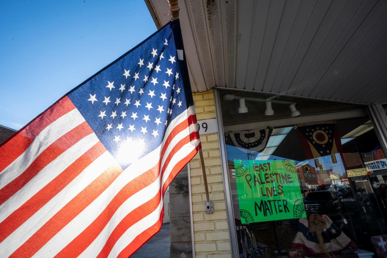 Feb 21, 2023; East Palestine, Ohio, USA;  Signs and an American Flag decorate the front of Flowers and Gifts Straight from the Heart in East Palestine. Mandatory Credit: Brooke LaValley/Columbus Dispatch