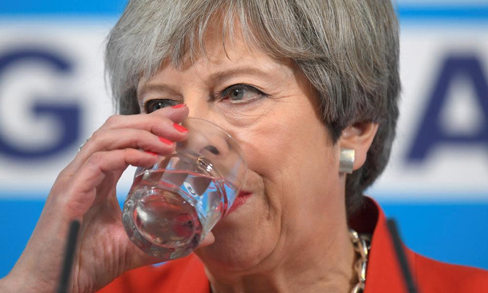 Theresa May holds a glass to her lips