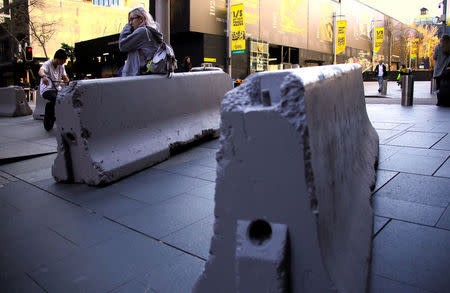 A woman rests on a concrete block that was placed by authorities as extra security measures at Sydney's Martin Place in Australia, July 18, 2017. REUTERS/David Gray