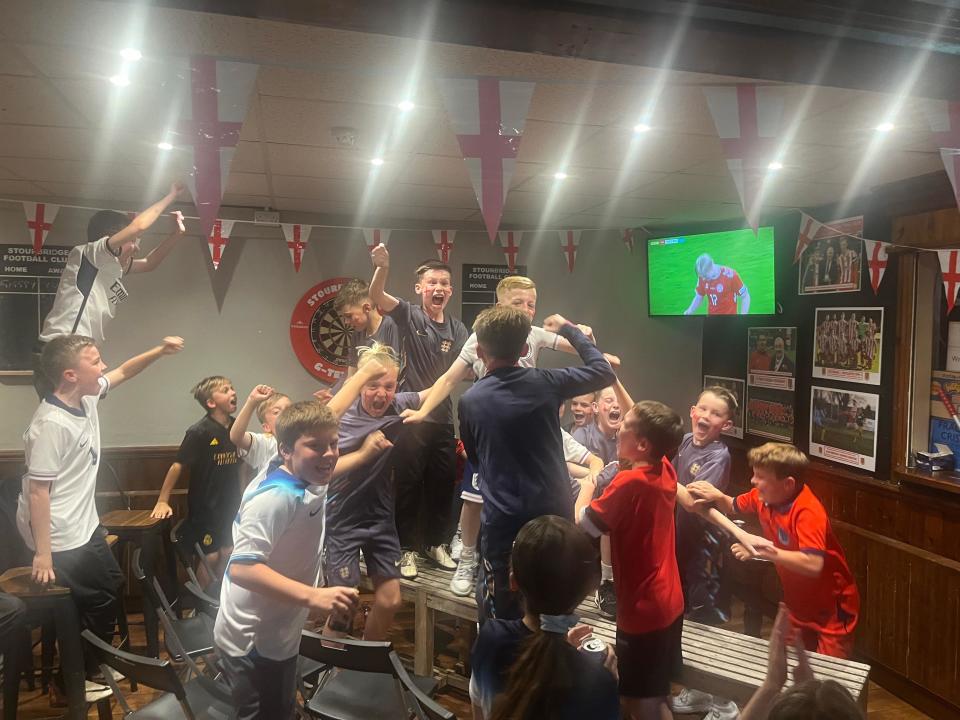 The children of Stourbridge cheer England's goal in front of a TV screen