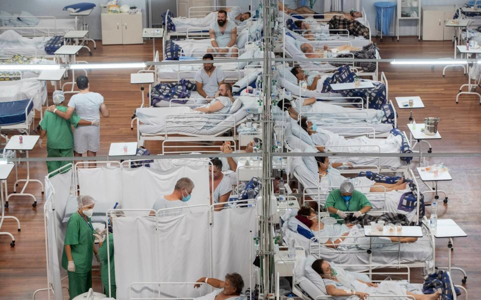 Covid-19 patients lie on beds at a field hospital built inside a sports coliseum in Santo Andre, on the outskirts of Sao Paulo, Brazil - Andre Penner /AP