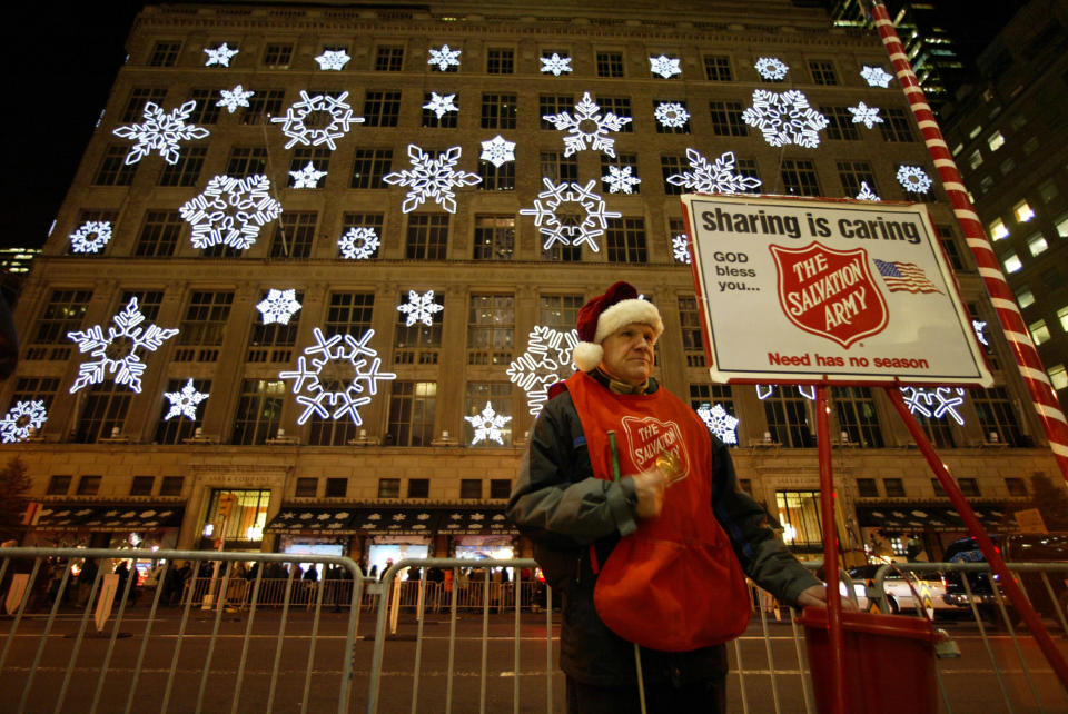 Reed Devlin, a blind Salvation Army volunteer, rings his bell across the street from the holiday windows and snow flake light show of Saks Fifth Avenue  Monday, Dec. 13, 2004.   Each holiday season the stores in midtown Manhattan try to out do each other in creating the most original displays to attract visitors from around the country and the world - and their money.  (AP Photo/Mary Altaffer)