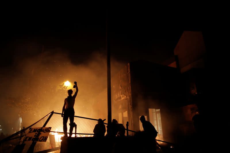 Protesters gather around after setting fire to the entrance of a police station as demonstrations continue in Minneapolis