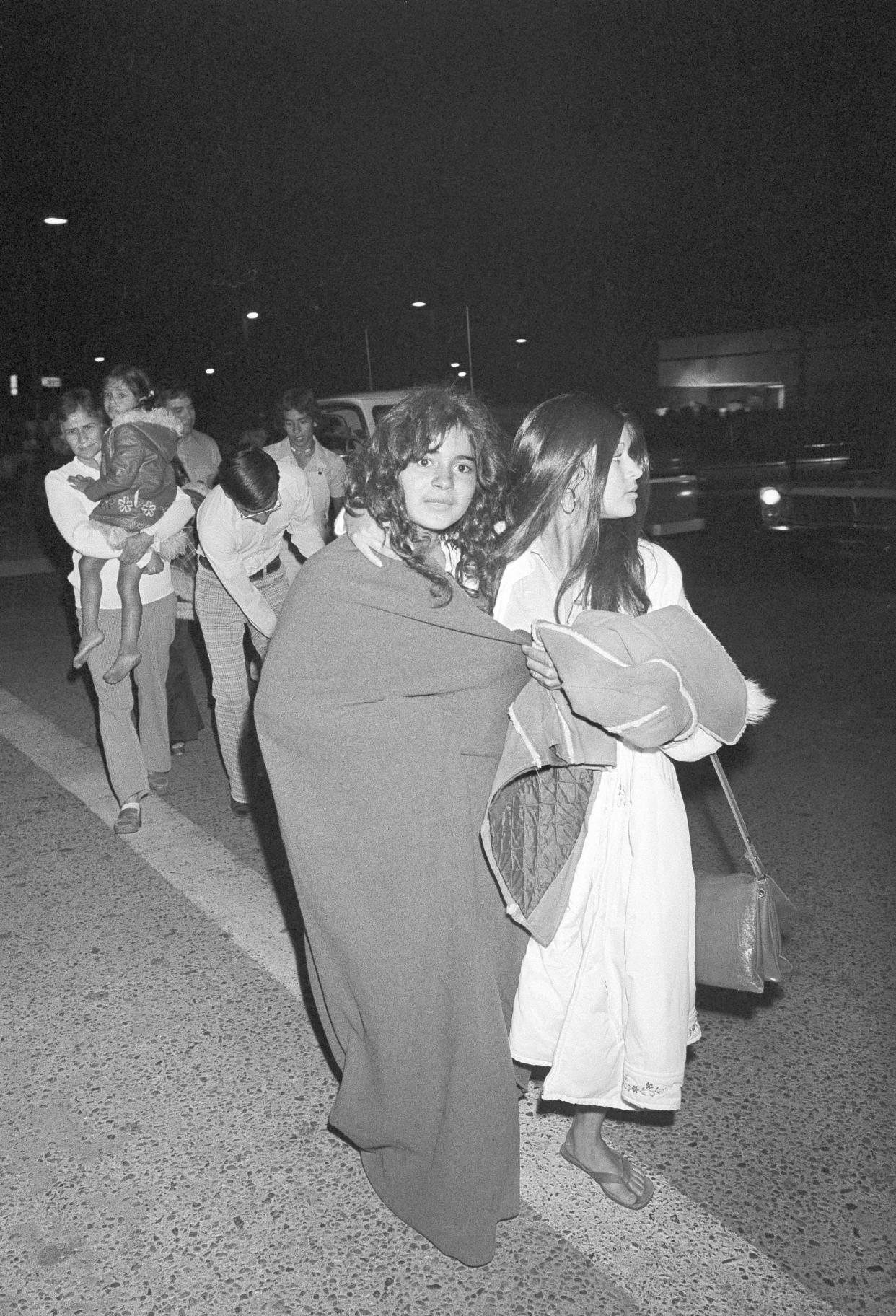FILE - Two Dairyland Union School District students, who were among the 26 school children, and their bus driver who were abducted and buried in a truck underground, walk to the family car clad in blankets after release and early morning arrival in Chowchilla, Calif., on July 17, 1976. California parole commissioners have recommended parole for the last of three men convicted of hijacking the school bus full of children for $5 million ransom in 1976. The two commissioners acted Friday, March 25, 2022, in the case of 70-year-old Frederick Woods. (AP Photo, File)