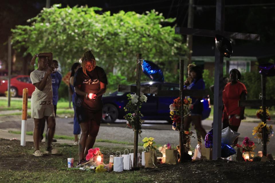 People pay their respects on Aug. 28 at a vigil constructed with crosses and a mural at Almeda Street and Kings Road in Jacksonville. Two days earlier a white gunman shot and killed three Black victims at the Dollar General store about a block away. The three victims included Angela Michelle Carr, Anolt Joseph “AJ” Laguerre Jr. and Jerrald De'Shaun Gallion.