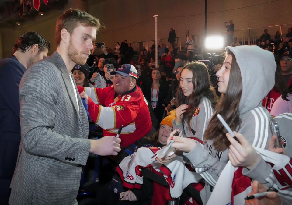 Edmonton Oilers captain Connor McDavid, left, signs autographs for fans during the NHL All-Star week hockey festivities in Toronto on Thursday, Feb. 1, 2024. (Frank Gunn/The Canadian Press via AP)