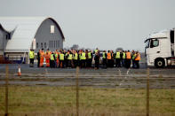 Truck drivers huddle together as some 150 trucks gather at Manston Airfield during a 'no-deal' Brexit test, to assess where 6,000 trucks could be parked at the former airfield near Ramsgate in south east England, Monday, Jan. 7, 2019. The derelict airfield at Manston could be used as part of a government plan to park trucks to alleviate expected congestion at the channel ports, about 25 miles (40 Km) from the airfield, caused by the reintroduction of customs checks on goods in the event of Britain making a no-deal withdrawal from the European Union at the end of March. (AP Photo/Matt Dunham)