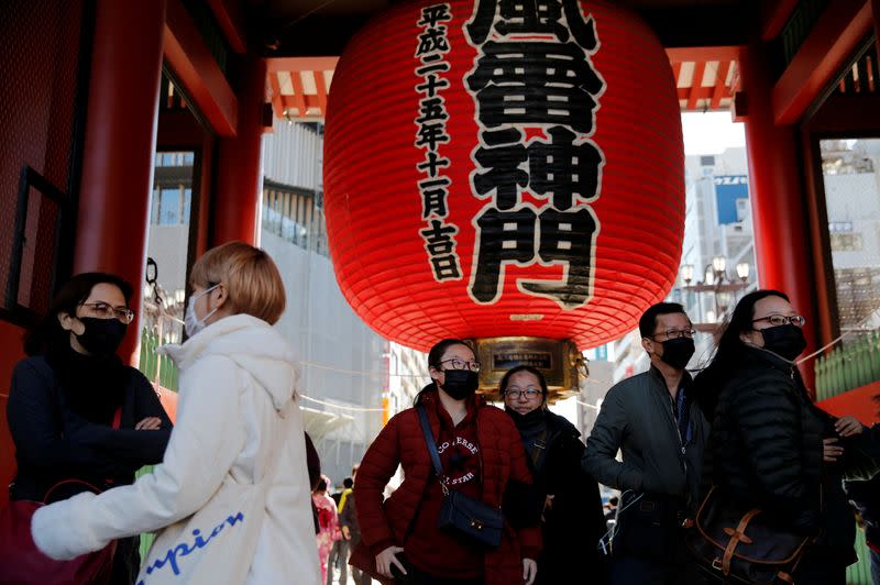 Tourists wearing face masks walk past Kaminarimon Gate as they visit Sensoji temple in Tokyo