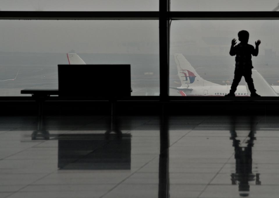 Un niño mira por la ventana a la pista, donde están varios aviones de Malaysia Airlines, en el aeropuerto internacional de la bahía de Kuala Lumpur, en Sepang, el 14 de marzo de 2014