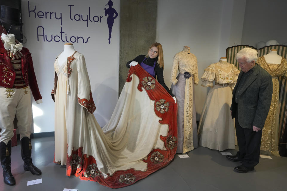 A costume handler arranges Kate Winslet's costume as Sylvia Llewelyn Davies in the film Finding Neverland, 2004 as John Bright, right, looks on, as it is displayed at Kerry Taylor Auctions in London, Tuesday, Feb. 27, 2024. The costume estimated at 1,500-2,500 UK Pounds (1,900-3,200 US Dollars) is one of 69 that will be for auction in the Lights Camera Auction event on March 5. The costumes have been donated by Cosprop in support of The Bright Foundation, an arts education charity, established and funded by John Bright, to provide life-enhancing, creative experiences for children and young people facing disadvantage. (AP Photo/Kirsty Wigglesworth)