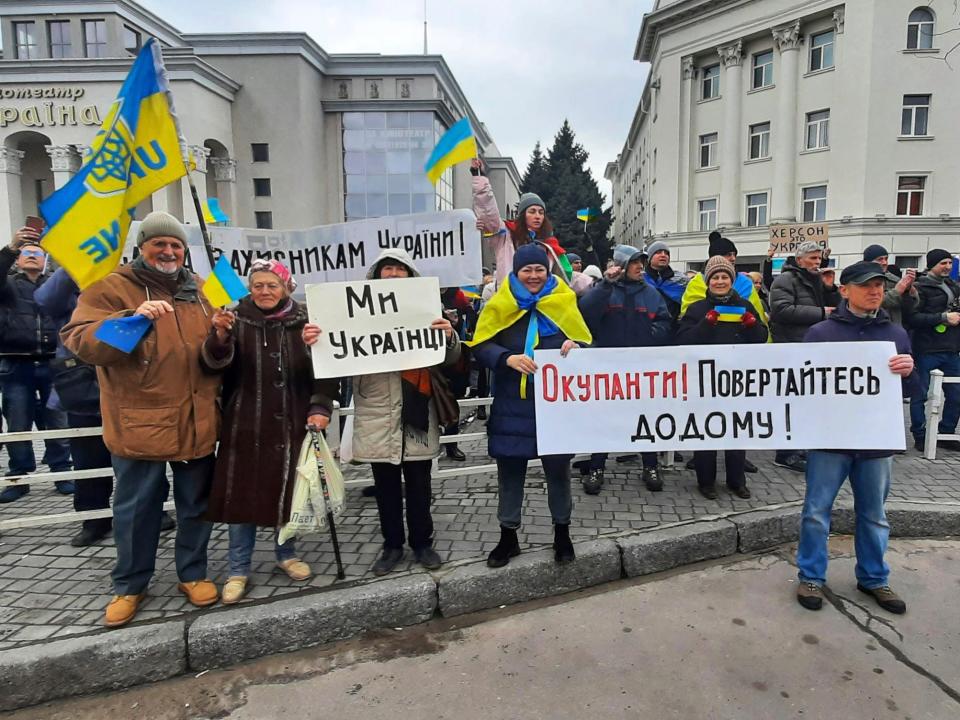 A crowd of Ukrainians stand with protest signs.