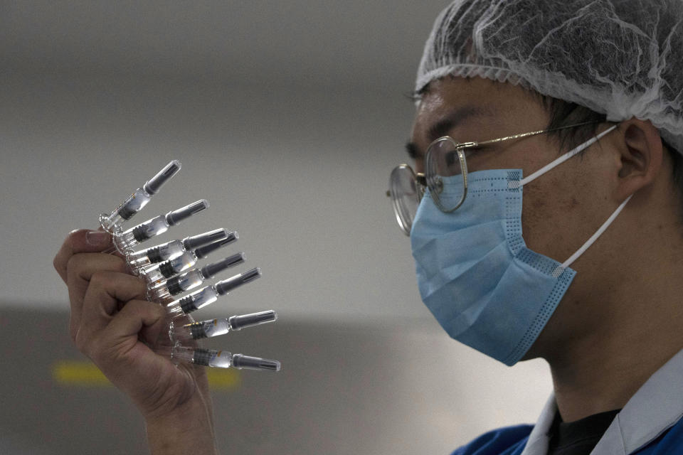 An employee manually inspects syringes of the SARS CoV-2 Vaccine for COVID-19 produced by SinoVac at its factory in Beijing on Thursday, Sept. 24, 2020. A Chinese health official said Friday, Sept. 25,2020, that the country's annual production capacity for coronavirus vaccines will top 1 billion doses next year, following an aggressive government support program for construction of new factories. (AP Photo/Ng Han Guan)