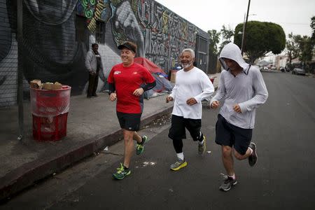 Runners from the Midnight Mission Running Club, Tom Cohen (L-R), Oscar Knight, 53, and Seth Becker, 22, run through Skid Row in Los Angeles, California April 20, 2015. REUTERS/Lucy Nicholson