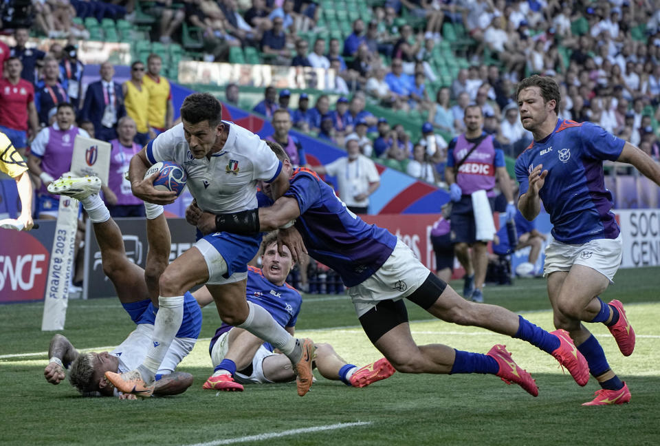 Italy's Tommaso Allan, left, runs for a try as Namibia's Johan Deysel tries to stop him during the Rugby World Cup Pool A match between Italy and Namibia at the Geoffroy Guichard stadium in Saint-Etienne, central France, Saturday, Sept. 9, 2023. (AP Photo/Laurent Cipriani)