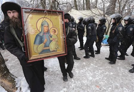 Priests carry an Orthodox icon past riot police on duty outside the Parliament in Kiev January 28, 2014. REUTERS/Konstantin Chernichkin