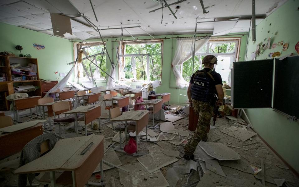 A police officer checks a school during an evacuation of local residents between shelling in the town of Marinka in Donetsk - STRINGER/REUTERS