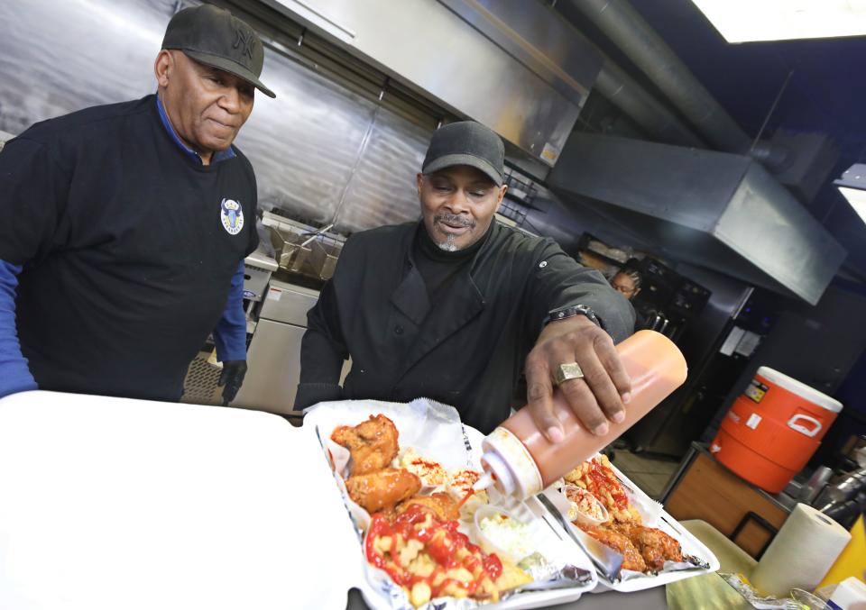 Owner Richard Gause, right, and his uncle Bernie Gause, sauce up a 3 Wing Snack Pack at the new G & G Steakout II.