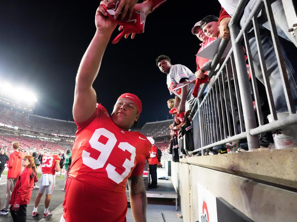 Ohio State defensive tackle Hero Kanu gives his gloves to a fan following a win over Western Michigan on Sept. 7.