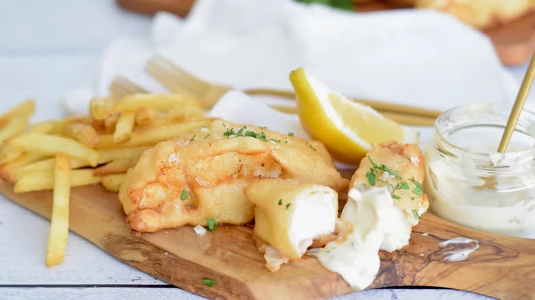 Fried fish and French fries on board with tartar sauce