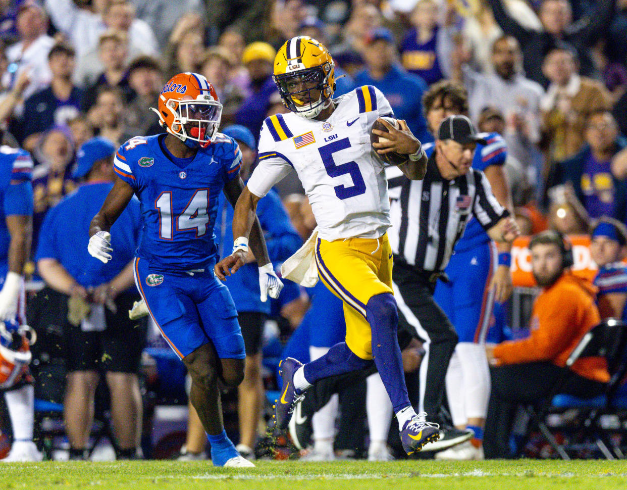 LSU Tigers quarterback Jayden Daniels (5) rushes for a touchdown against Florida Gators safety Jordan Castell (14) during the first half at Tiger Stadium.