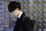 A man walks by an electronic stock board of a securities firm in Tokyo, Wednesday, Jan. 20, 2021. Asian shares were mostly higher Wednesday, ahead of Joe Biden's inauguration as president, ending President Donald Trump’s four-year term. Japan's benchmark lost early gains as worries grew about the surge in coronavirus cases. (AP Photo/Koji Sasahara)