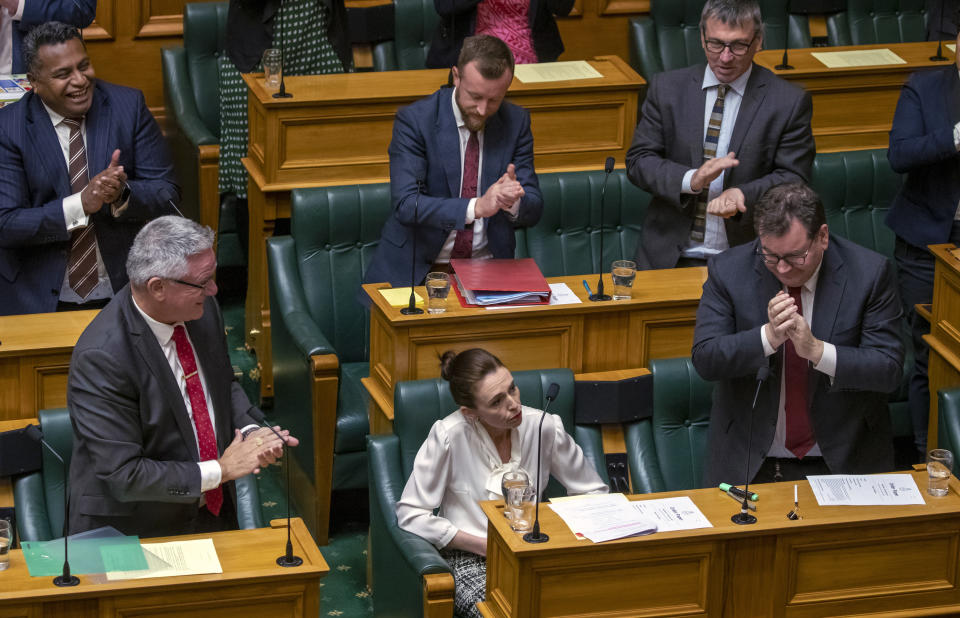 New Zealand's Prime Minister Jacinda Ardern, bottom center, is applauded after moving a motion in the Parliament House in Wellington, New Zealand, to declare a climate emergency, Wednesday, Dec. 2, 2020. Joining more than 30 other countries around the world, New Zealand took the symbolic step of declaring a climate emergency. (Mark Mitchell/New Zealand Herald via AP)
