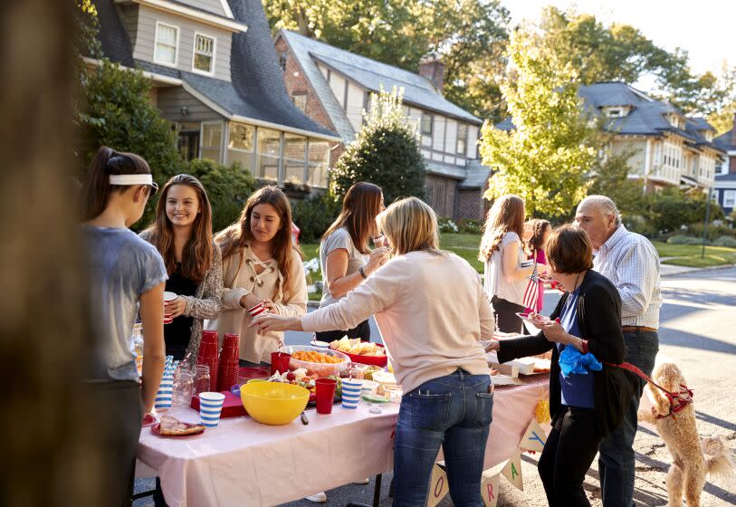 Neighbors chat around a table at a block party.