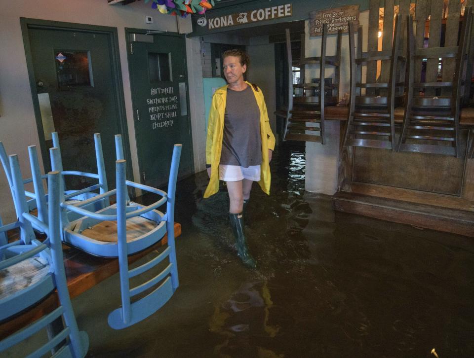 Aimee Cutter the owner of Beach House restaurant walks through water surge from Lake Pontchartrain on Lakeshore Drive in Mandeville, La., ahead of Tropical Storm Barry, Saturday, July 13, 2019. Barry is expected to reach hurricane strength by the time its center reaches the Louisiana coast, expected before noon local time. The storm is expected to weaken after it moves inland. (AP Photo/Matthew Hinton)